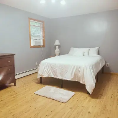 a bedroom with a white bed and a wooden floor at Quiet Cozy Stay Spacious Home Near Beach & Shops in Hamden