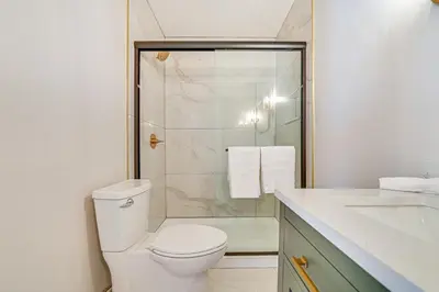 a white bathroom with a toilet and a shower at Saratoga Springs Home with Hot Tub Walk to Downtown in Saratoga Springs
