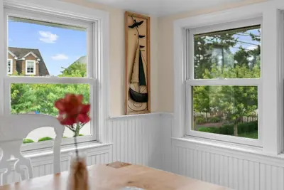a dining room with two windows and a table at Charming Fairfield Cottage By The Sea in Fairfield