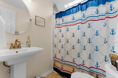 a bathroom with a sink and a shower curtain with blue anchors at Charming Fairfield Cottage By The Sea in Fairfield