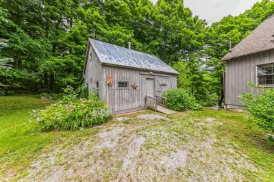 a gray barn with a porch and a building at Bear Pass - Mountain View home in Sunderland