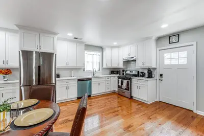 a kitchen with white cabinets and a wooden table with a tableablish at 2 Mi to Dtwn Well-Appointed Bridgeport Duplex! in Bridgeport