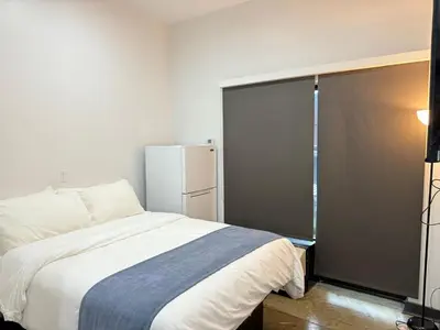 a bedroom with a white bed and a refrigerator at Tribeca Hotel FiDi in New York