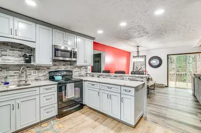 a kitchen with white cabinets and a red wall at Wooded Tobyhanna Home with Fire Pit and Lake Access! in Tobyhanna