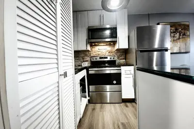 a kitchen with white cabinets and stainless steel appliances at Lux Apt in Beacon