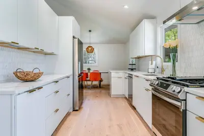 a kitchen with white cabinets and a wooden floor at New Paltz Modern Zen Cabin in New Paltz