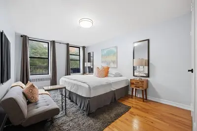 a bedroom with a bed and a chair and windows at The Lenox in New York
