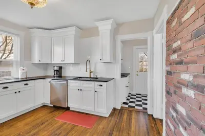 a kitchen with white cabinets and a brick wall at Prime West Hartford Center- Timeless Charm in West Hartford