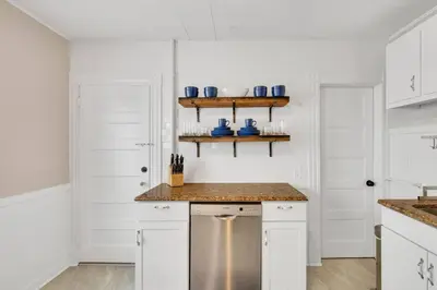 a kitchen with white cabinets and a silver dishwasher at Classic West Hartford Center Apartment in West Hartford