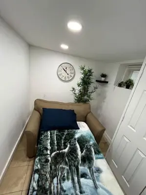 a bed in a room with a clock on the wall at 2 Bedroom Apartment By AirportS in Hillside