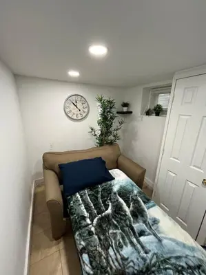a living room with a couch and a clock on the wall at 2 Bedroom Apartment By AirportS in Hillside