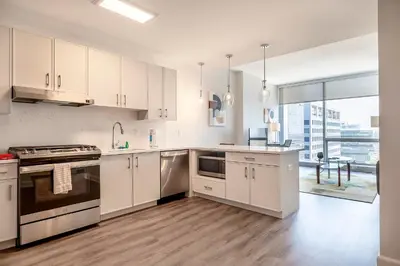 a kitchen with white cabinets and a large window at Private Apt with Gym & Pool in Stamford