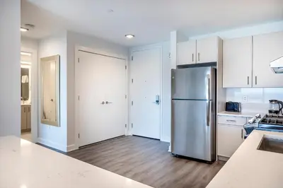 a kitchen with a stainless steel refrigerator and white cabinets at Private Apt with Gym & Pool in Stamford