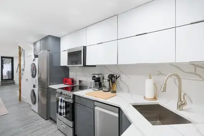 a kitchen with white cabinets and stainless steel appliances at 317-1D New 2BR Duplex WD Private Backyard in New York