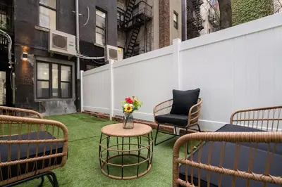 a patio with chairs and a table with a vase of flowers at 317-1D New 2BR Duplex WD Private Backyard in New York