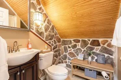 a bathroom with a toilet and a stone wall at The Beautiful & Cozy Malvec Chalet in Tobyhanna
