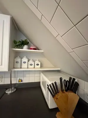 an attic kitchen with white cabinets and black utensils at Cozy studio quiet in Trumbull
