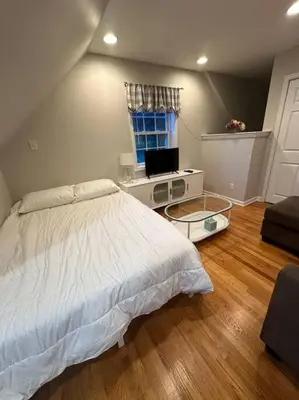 a bedroom with a bed and a desk with a television at Cozy studio quiet in Trumbull