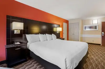 a hotel room with a large bed with white sheets at BEST WESTERN PLUS Poconos in Tannersville