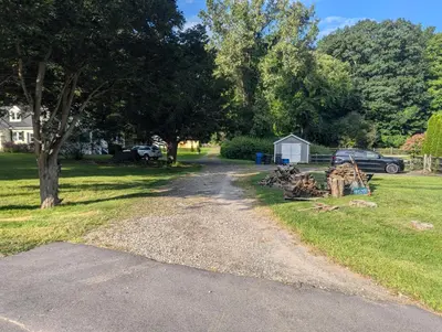 a dirt road with a car parked in a yard at Tranquil Getaway Cottage in Charming, Bethel CT in Bethel