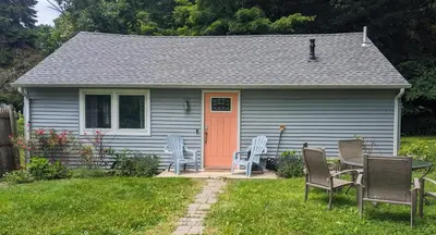 a small house with an orange door and chairs at Tranquil Getaway Cottage in Charming, Bethel CT in Bethel