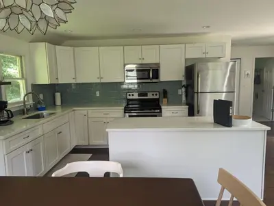 a kitchen with white cabinets and stainless steel appliances at Tranquil Getaway Cottage in Charming, Bethel CT in Bethel