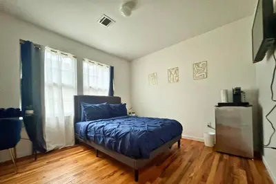 a bedroom with a bed with a blue comforter at Belmont Suites - BR 2 (Private Room) - 30 mins to NYC in Newark