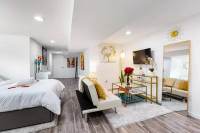 a bedroom with a large bed and a living room at Luxury Suite by Prudential Ctr & 7min to EWR Airpt in Newark