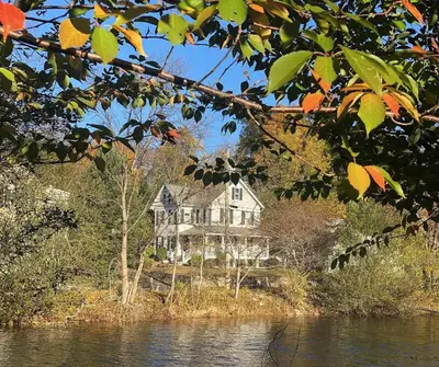 a large house sitting on the side of a river at Stylish Victorian Beach House on pond in Rowayton