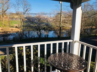 a table on a porch with a view of the water at Stylish Victorian Beach House on pond in Rowayton