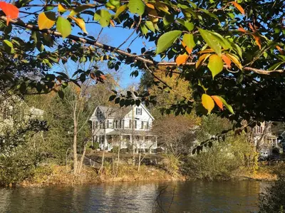 a large house sitting on the side of a river at Stylish Victorian Beach House on pond in Rowayton