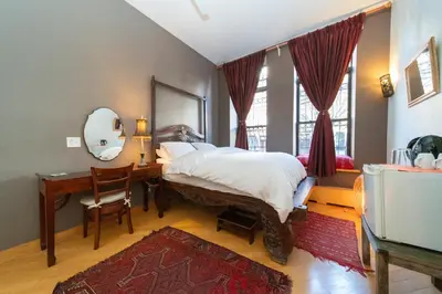 a bedroom with a bed and a desk and a mirror at 2 bedrooms with one private bathroom in lovely home in New York