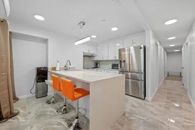 a kitchen with white cabinets and an island with orange chairs at Active Central Park East 3bedrooms 2 bathrooms 1700 SF in New York