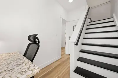 a staircase in a white room with a table and a chair at NYC Access 4BR Duplex Sleeps 10, Free Parking in Fair Lawn