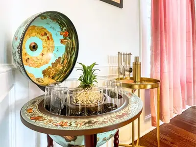 a table with glasses and a large globe on it at The Jewel of The Cove - Historic Coastal Retreat in New Haven