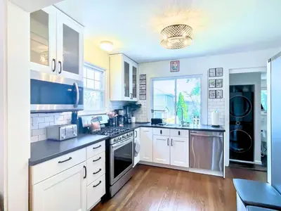 a kitchen with white cabinets and a stove top oven at The Jewel of The Cove - Historic Coastal Retreat in New Haven