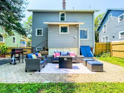 a patio with couches and a table in front of a house at The Jewel of The Cove - Historic Coastal Retreat in New Haven
