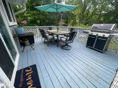 a wooden deck with a grill and a table with chairs and an umbrella at Welcome to our Retreat Haven in Warwick, NY in Warwick