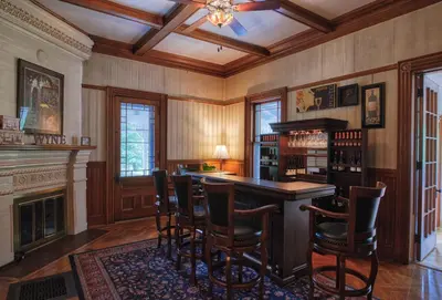 a kitchen with a bar with chairs and a fireplace at Rockwell Falls Inn and Wine Bar in Lake Luzerne