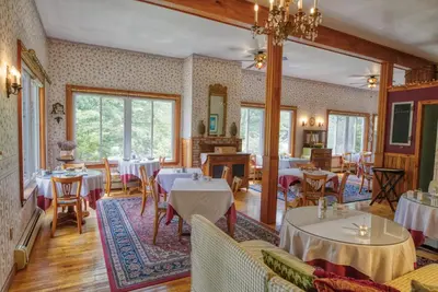 a restaurant with tables and chairs in a room at Rockwell Falls Inn and Wine Bar in Lake Luzerne