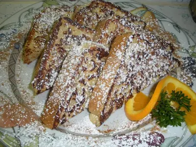 a plate of french toast with orange slices and powdered sugar at Rockwell Falls Inn and Wine Bar in Lake Luzerne