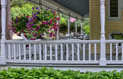 a porch with a white rail and flowers on it at Rockwell Falls Inn and Wine Bar in Lake Luzerne