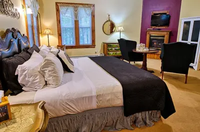 a bedroom with a large bed and a table and chairs at Rockwell Falls Inn and Wine Bar in Lake Luzerne