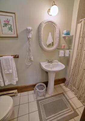 a bathroom with a sink and a mirror at Rockwell Falls Inn and Wine Bar in Lake Luzerne