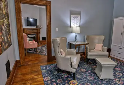 a living room with chairs and a table and a mirror at Rockwell Falls Inn and Wine Bar in Lake Luzerne