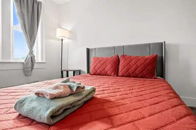 a bedroom with a red bed with a red blanket and a window at Downtown Hartford 2BR Family Pet Friendly in Hartford