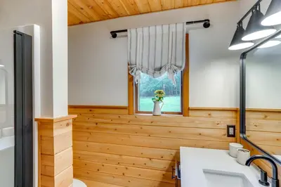 a bathroom with wood paneling and a window at Stylish Catskills Retreat Year-Round Adventure! in Round Top