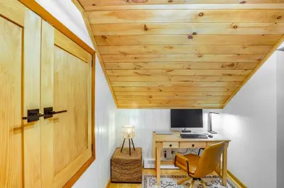 an attic room with a wooden door and a desk at Stylish Catskills Retreat Year-Round Adventure! in Round Top