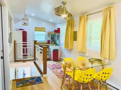 a dining room with a glass table and yellow chairs at Red Peacock Catskill Cabin sleeps four 6 in Shandaken