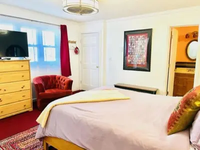 a bedroom with a bed and a tv and a chair at Red Peacock Catskill Cabin sleeps four 6 in Shandaken